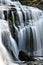 Mountain waterfall dropping over smooth moss rocks.