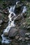 A mountain waterfall flows over the rocks. Waterfall cascade on mossy rocks