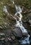 A mountain waterfall flows over the rocks. Waterfall cascade on mossy rocks