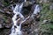 A mountain waterfall flows over the rocks. Waterfall cascade on mossy rocks