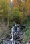 A mountain waterfall flows over the rocks. Waterfall cascade on mossy rocks