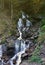 A mountain waterfall flows over the rocks. Waterfall cascade on mossy rocks