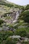 Mountain waterfall in High Tatras Skok. Tall rocks covered with scrub