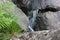 Mountain waterfall. Mountain river among gray huge boulders in the middle of a dense forest