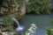 Mountain waterfall. Powerful jets of water flow into the lake, illuminated by the sun.