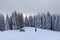 Mountain winter landscape. Tourist stands on the path next to the green tent. Wild forest. Touristic camping rest place.