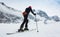 Mountaineer backcountry ski walking up along a snowy ridge with skis in the backpack. In background blue sky and shiny