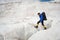 A mountaineer with a backpack walks in crampons walking along a dusty glacier with sidewalks in the hands between cracks