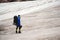 A mountaineer with a backpack walks in wheelchairs, stands on a dusty glacier with sneakers in the hands between cracks