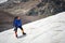 A mountaineer with a backpack walks in wheelchairs, stands on a dusty glacier with sneakers in the hands between cracks