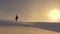 Mountaineer with camera and tripod is walking in snow along top of a holom. photographer traveler in winter goes on