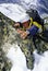 Mountaineer climbing snowy rock face