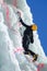 Mountaineer climbs an icefall in Alps of Piedmont, Italy