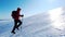 Mountaineer climbs a snowy mountain over blue clear sky. Winter