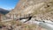 Mountaineer crossing a small bridge over a high mountain glacial stream