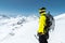 A mountaineer man holds an ice ax high in the mountains covered with snow. View from the back. outdoor extreme outdoor