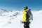 A mountaineer man holds an ice ax high in the mountains covered with snow. View from the back. outdoor extreme outdoor