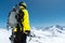 A mountaineer man holds an ice ax high in the mountains covered with snow. View from the back. outdoor extreme outdoor