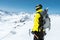 A mountaineer man holds an ice ax high in the mountains covered with snow. View from the back. outdoor extreme outdoor