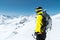 A mountaineer man holds an ice ax high in the mountains covered with snow. View from the back. outdoor extreme outdoor