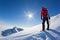 Mountaineer reaches the top of a snowy mountain in a sunny winter day.