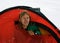 Mountaineer in a red tent on snow in the mountains of Pamir
