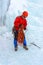 Mountaineer standing under the glacier is preparing a rope for climbing