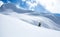 Mountaineer walking up along a snowy ridge. In background a shiny bright sun