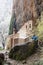 Mountaineer wetting his hand in a waterfall in front of an hermitage