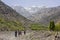 Mountaineers caravan hiking over a huge valley of the great atlas of morocco with huge snowy mountains in the background