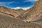 Mountaineers and donkeys carrying climbing equipment on a mountain path to the base camp of Stok Kangri peak at 5500m