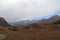 Mountains in autumn with brown and reddish grass under cloudy sky