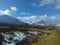 Mountains of Glencoe stand covered in snow under wintry blue skies as snow melts into the river on Rannoch Moor