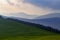 Mountains in the haze at sunset. Alpine mountain green meadow and forest at sunset in the mountains in the background. Mountain