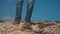 In the mountains, a man in a cowboy hat, leather jacket, blue jeans with a large tourist backpack.