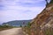 Mountains road with old road sign. blue windy sky and sea background