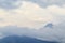 Mountains of the Trans-Ili Alatau behind a layer of clouds, fog under gray clouds in cloudy weather.