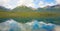 Mountains and trees reflected in a calm lake along the cassiar highway