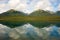 Mountains and trees reflected in a calm lake along the cassiar highway