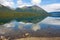 Mountains and trees reflected in a calm lake along the cassiar highway