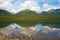 Mountains and trees reflected in a calm lake along the cassiar highway