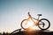 Mounted mountain bicycle silhouette on the car roof with evening sun light rays background. Safe sport items transportation using