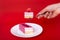 Mousse cake in a woman`s hand with raspberries on a red background