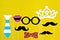 Moustache, tie, glasses, red mouth on wooden sticks against a bright yellow background Month donations