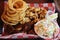 Mouth watering image of fried clams, onion rings, sea scallops and fresh coleslaw on table at restaurant