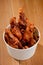 Mouthwatering fried chicken drumsticks in paper bucket