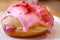 Mouthwatering strawberry-glazed with raspberry cream filling doughnut on a white plate