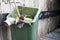 Movable street cleaning garbage bin with broom in it and gloves on the handle, without worker