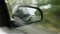 Movement in the car side mirror, view of the road. Reflection of a broken post-Soviet route with many pits.