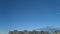 movement of clouds in the blue sky against the background of multi storey buildings.